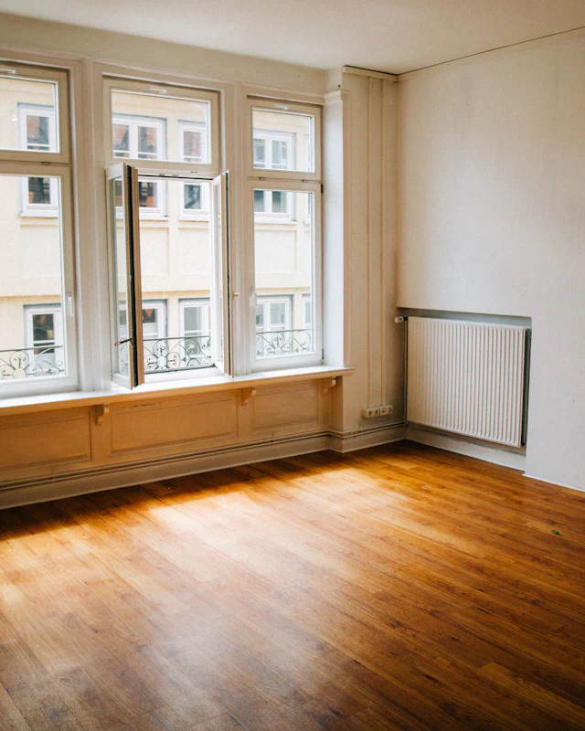 Empty sunlit room with wooden floors